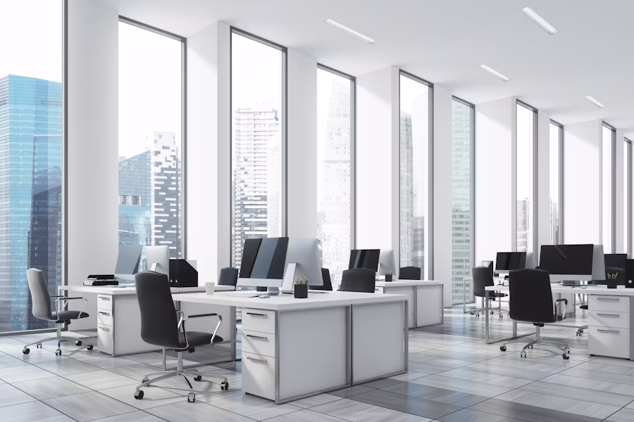 A bright office with desks and floor-to-ceiling windows